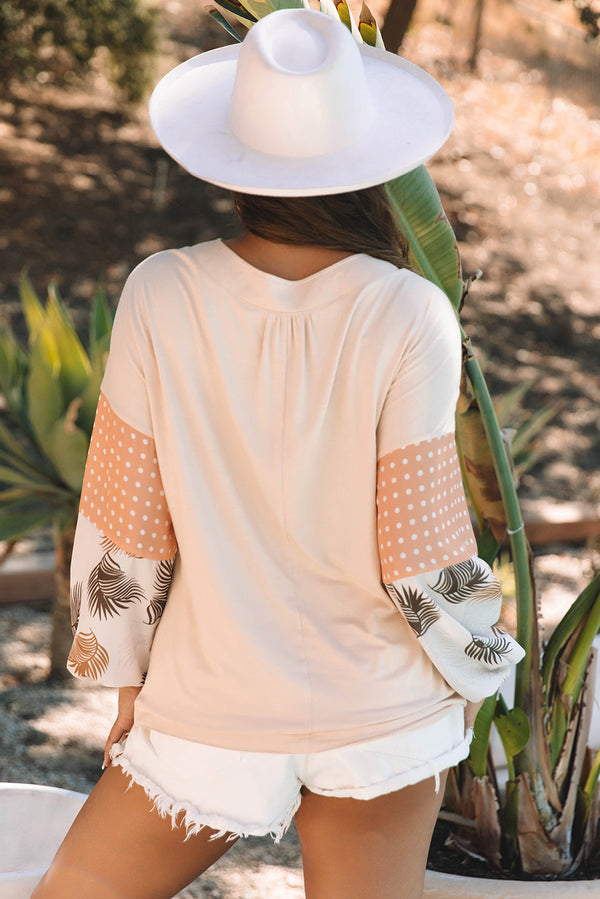 Blouse with puff sleeves and patchwork design, worn with hat in a natural outdoor setting.